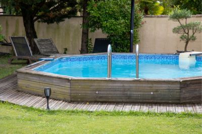 Piscine semi-enterrée en bois installée dans un jardin.